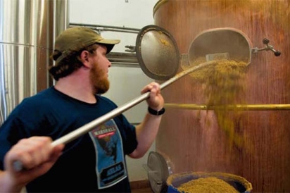Lucas Dewell removing spent grain from a tank after the brewing process